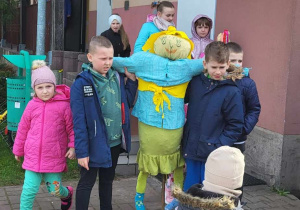 Uczniowie wychodzą z budynku szkoły z kukłą