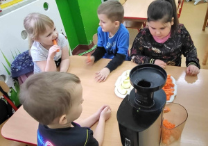 Gryzienie marchewki w tle z dziećmi i sokowirówka