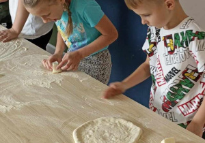 dzieci na tle dobrze przygotowanego ciasta na pizzę