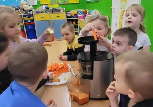 Dzieci wkładają marchewkę do sokowirówki