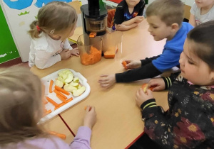 Dzieci wybierają owoce i warzywa i wkładają do sokowirówki