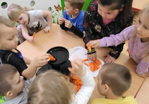 Dzieci wkładają warzywa do sokowirówki