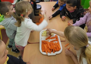 Dzieci wkładają gruszkę do sokowirówki