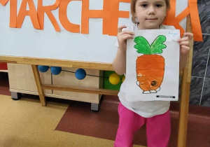Ilustracja pokolorowanego obrazka marchewki w rękach dziecka