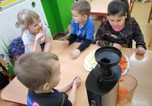 Gryzienie marchewki w tle z dziećmi i sokowirówka