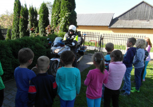 Policjant na motorze pozuje przed dziećmi
