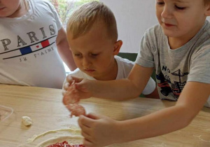 dzieci rozkładają salami na cieście